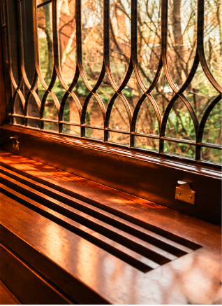 Hands sanding an old wood window frame